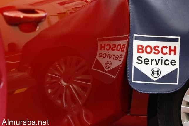 Service sign is reflected in car door while product expert for diagnostics equipment of German auto parts supplier Robert Bosch analyses a car in garage in Plochingen